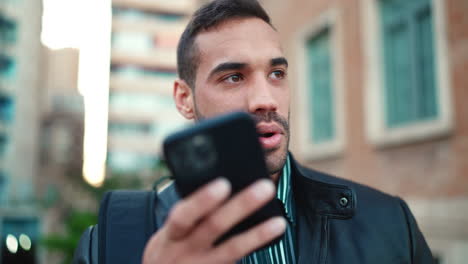 Young-man-recording-a-voice-message-on-smartphone-outdoors.