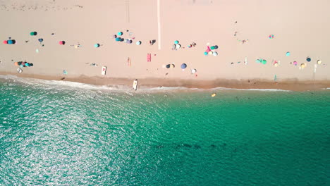 bird's eye view from above of the beach with colorful umbrellas and tourists in the beautiful tropical sea of emerald coast, sardinia, italy - aerial drone, static shot