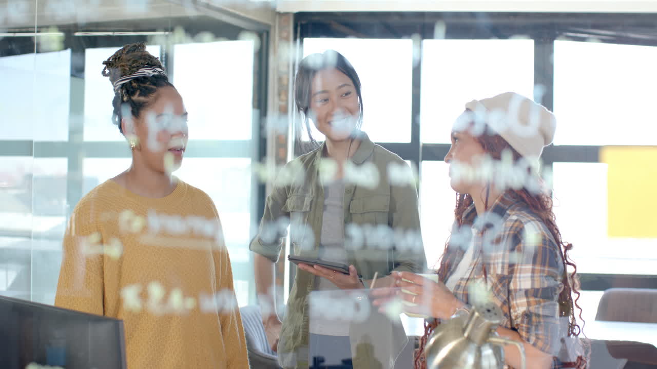 Diverse female team collaborating on coding project, brainstorming ideas on glass board in office