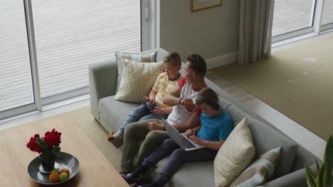 Caucasian-father-with-two-sons-sitting-in-living-room-and-using-laptop