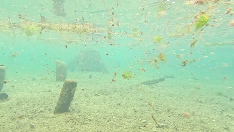 underwater view of a shallow body of water with debris and structures