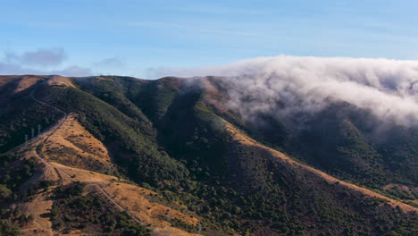 Wave-of-fog-rolls-over-a-mountain-ridge-and-burns-off---motion-time-lapse