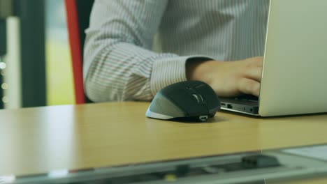 Caucasian-male-sitting-at-desk-working-remotely,-uses-laptop-and-mouse