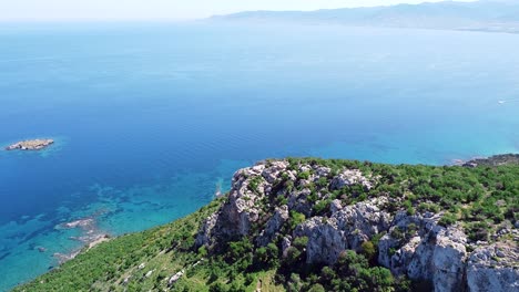 Aerial-view-from-the-top-of-Aphrodite-Nature-Trail,-showcasing-breathtaking-coastal-cliffs,-turquoise-waters,-and-distant-mountains