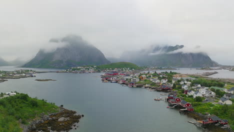 traditional red fishermen houses of reine lofoten with foggy mountains, aerial