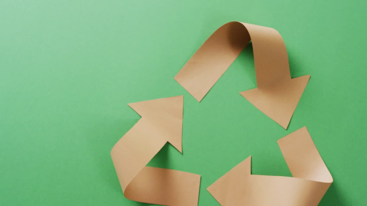 녹색 배경에 종이 화살표의 재활용 상징의 클로즈업, 복사 공간