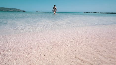 Mädchen,-Das-Aus-Dem-Meer-In-Richtung-Des-Rosafarbenen-Strandes-Geht