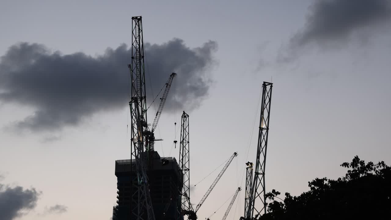 Silhouetted extreme swing ride launches above city skyline, dramatic dusk lighting, wide static shot