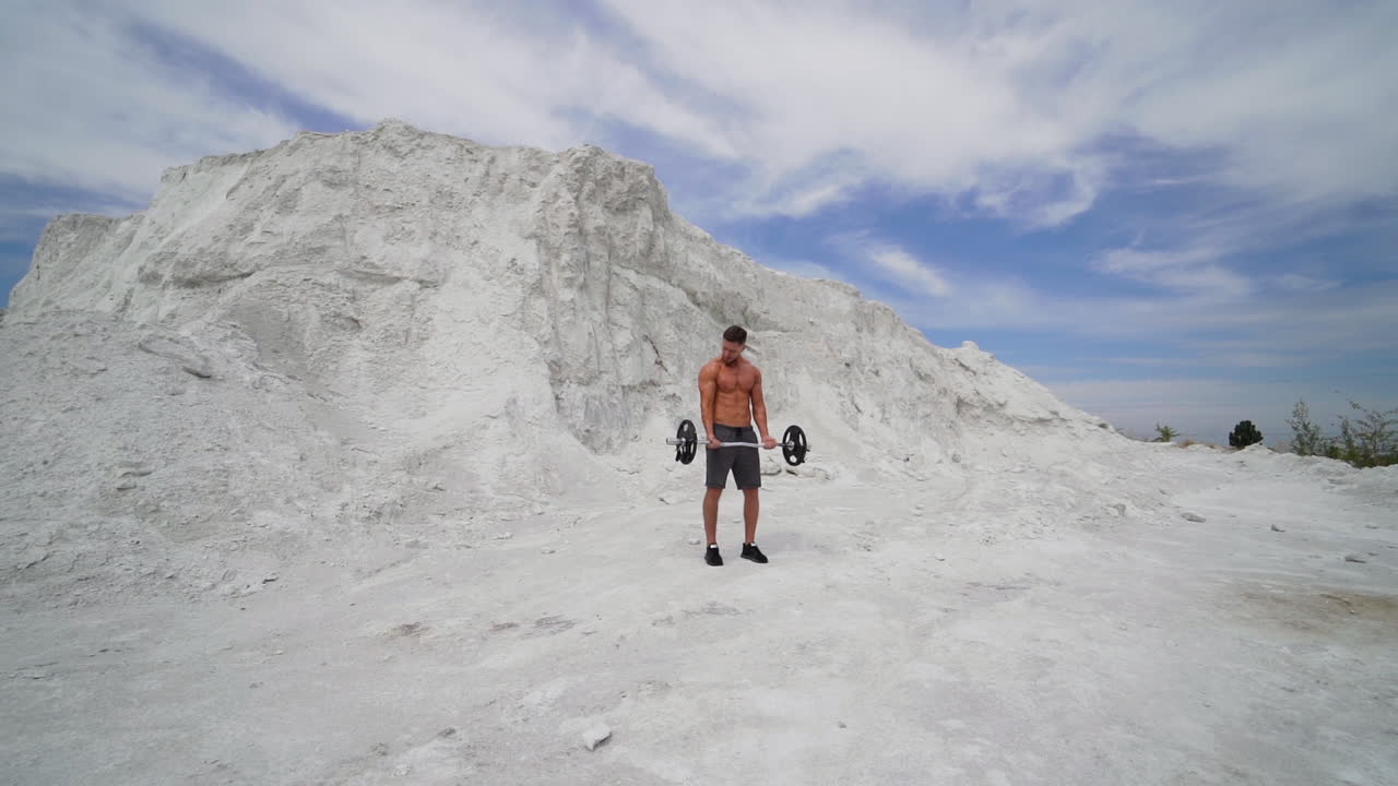Man with weight training on nature. Handsome man doing biceps lifting on nature