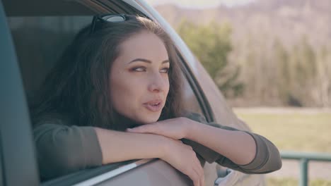 woman with sunglasses on head looks out of open auto window