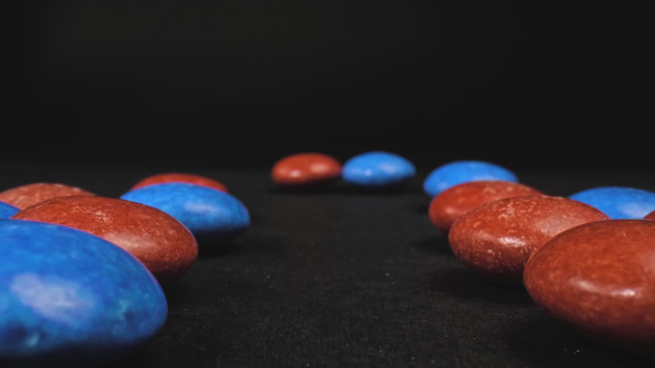 macro empuje en el disparo de caramelos rojos y azules en forma de botón con un fondo negro