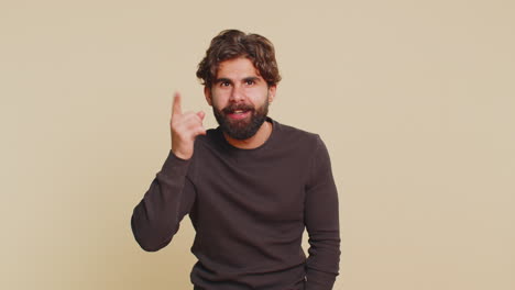 lebanese young man shakes finger saying no be careful scolding giving advice on beige background