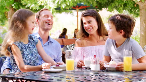 padres comiendo al aire libre en un café del parque con sus hijos