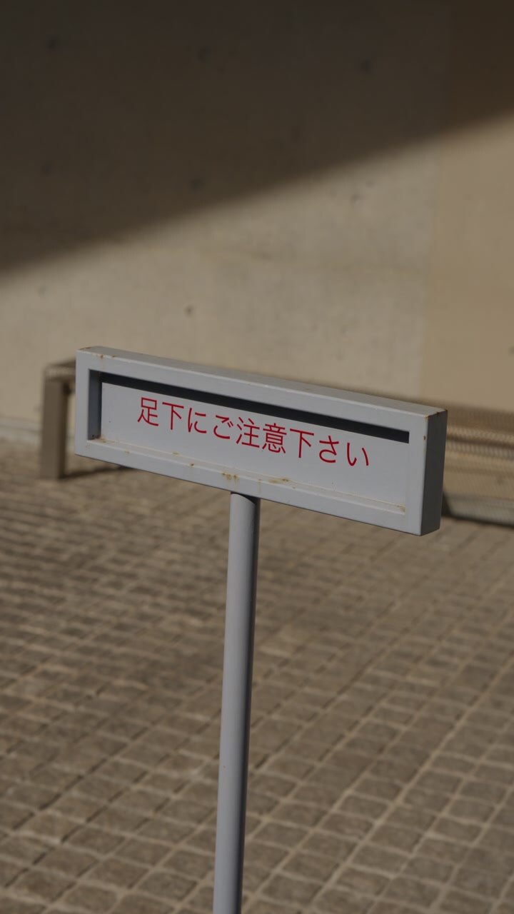vertical - Japanese watch your step warning sign on tiled floor Japan