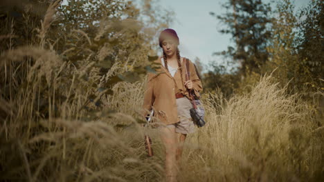 female explorer walking amidst grass by trees