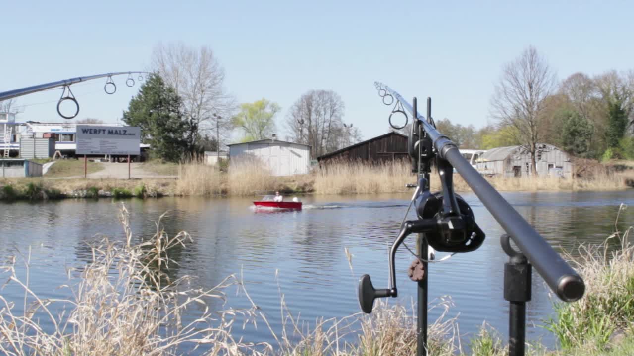 Fishing rod at riverside with a boat on the river