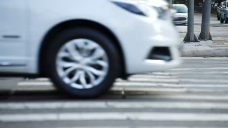 Cars-and-motorcycles-crossing-in-front-of-pedestrians-waiting-to-cross-the-crosswalk-of-a-big-city-in-daylight-filmed-in-slow-motion-in-4K-high-definition