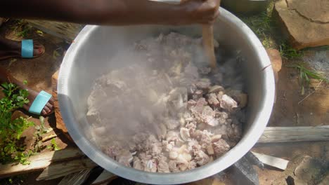 Close-up-shot-of-a-wooden-spoon-stirring-a-big-pot-of-a-meat-over-a-wood-fire