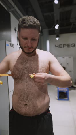 man measuring his body with tape measure in locker room