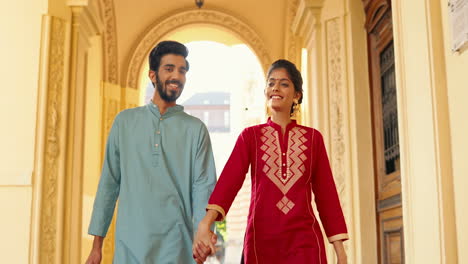 young indian couple walking, smiling and holding hands