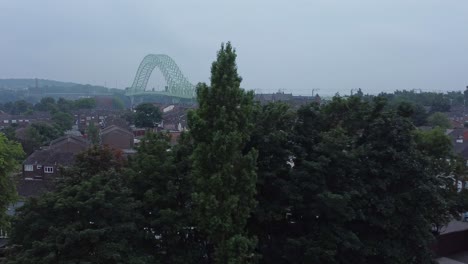 British-Northern-Runcorn-bridge-suburban-residential-townhouse-neighbourhood-aerial-view-dolly-right-behind-trees