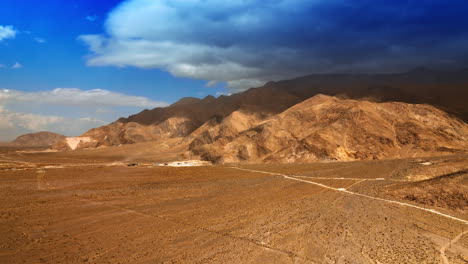 hot plain desert limited by bare rocks. huge cloudscape covering the mountain. lifeless scenery of death valley from top.