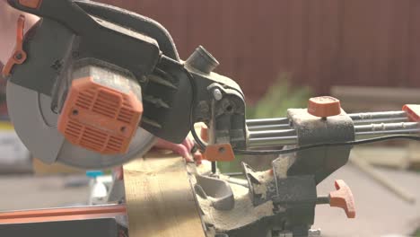 slow motion shot of a carpenter using a mitre saw to cut through decking boards