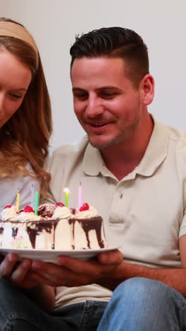 happy young family sitting on sofa celebrating a birthday