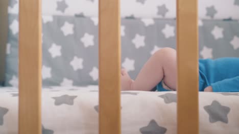 newborn kid lies in wooden crib with star decorated linen