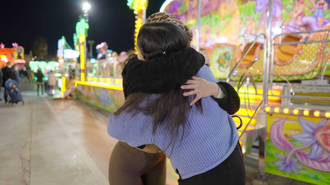 Two women hugging at a night fair