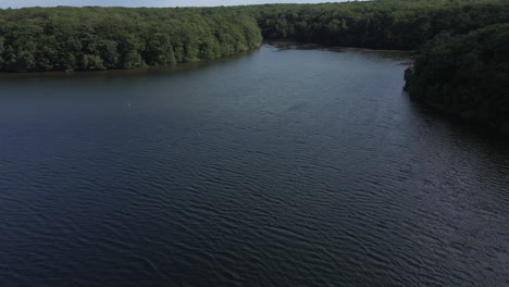 Flying-over-Tremelin-lake-at-low-altitude-over-water-surface,-Brittany-in-France