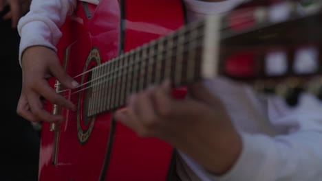 child playing red acoustic guitar