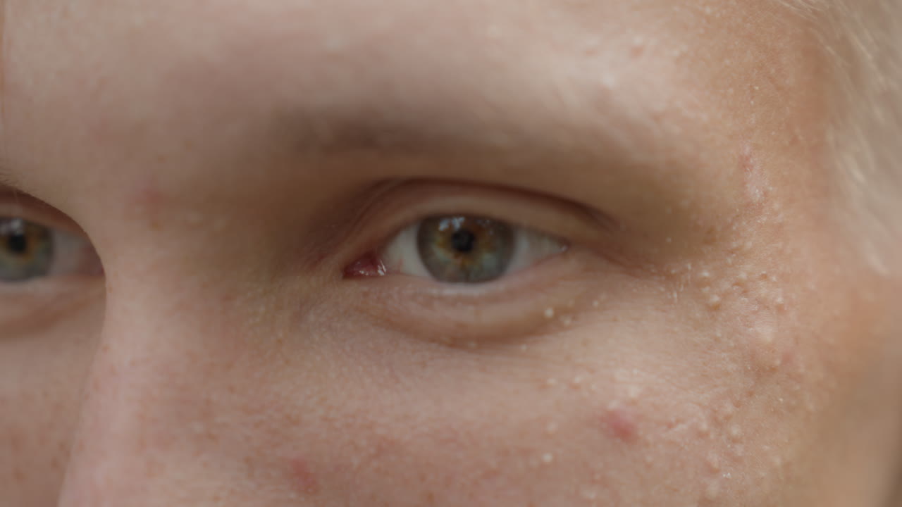 Un uomo gentile riconosce la luminosità in silenzio, una persona giovane socchiude gli occhi delicatamente a causa della luce intensa, un giovane individuo regola delicatamente gli occhi in risposta alla luminosità intensa
