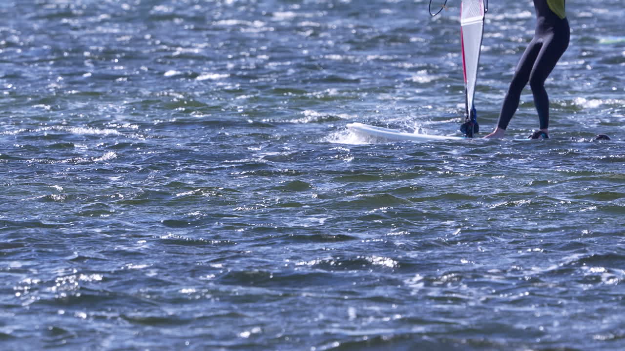 Windsurfer glides across choppy blue water on a sunny autumn day in Jurata Poland with dynamic movement and energy