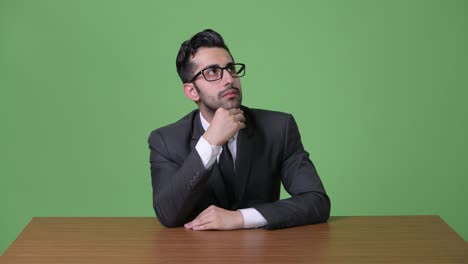 joven empresario persa barbudo y guapo contra un fondo verde
