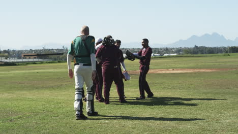 multiracial male baseball players and umpire huddle and taking picture on a pitch, slow motion