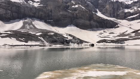 aerial view above the water surface of gletschersee at klausenpass, urner-boden, schweiz, highlighting klausenpass and the glacial lake griesslisee.