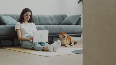 Junge-Frau,-Die-Zu-Hause-Neben-Ihrem-Hund-An-Ihrem-Laptop-Arbeitet