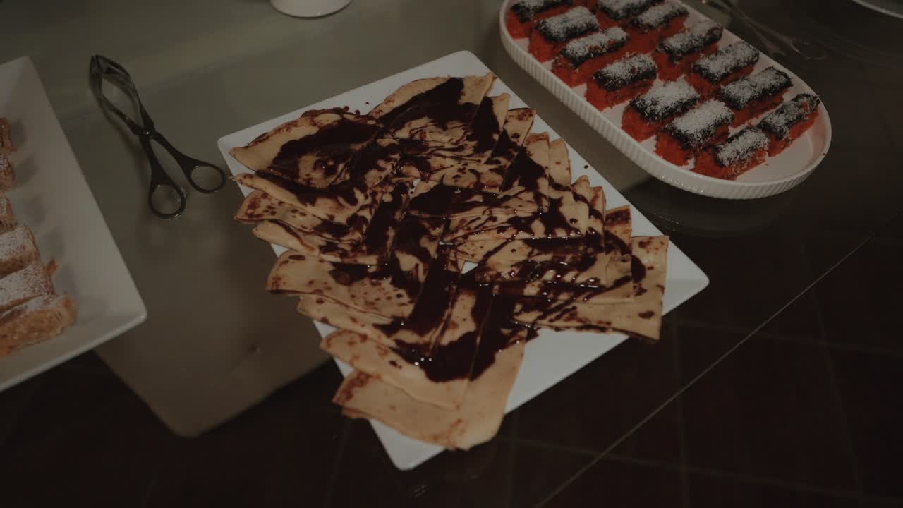 Plate of crepes drizzled with chocolate on buffet table