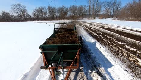 old manure spreader working on a winter field fertilizing the soil in southeast michigan