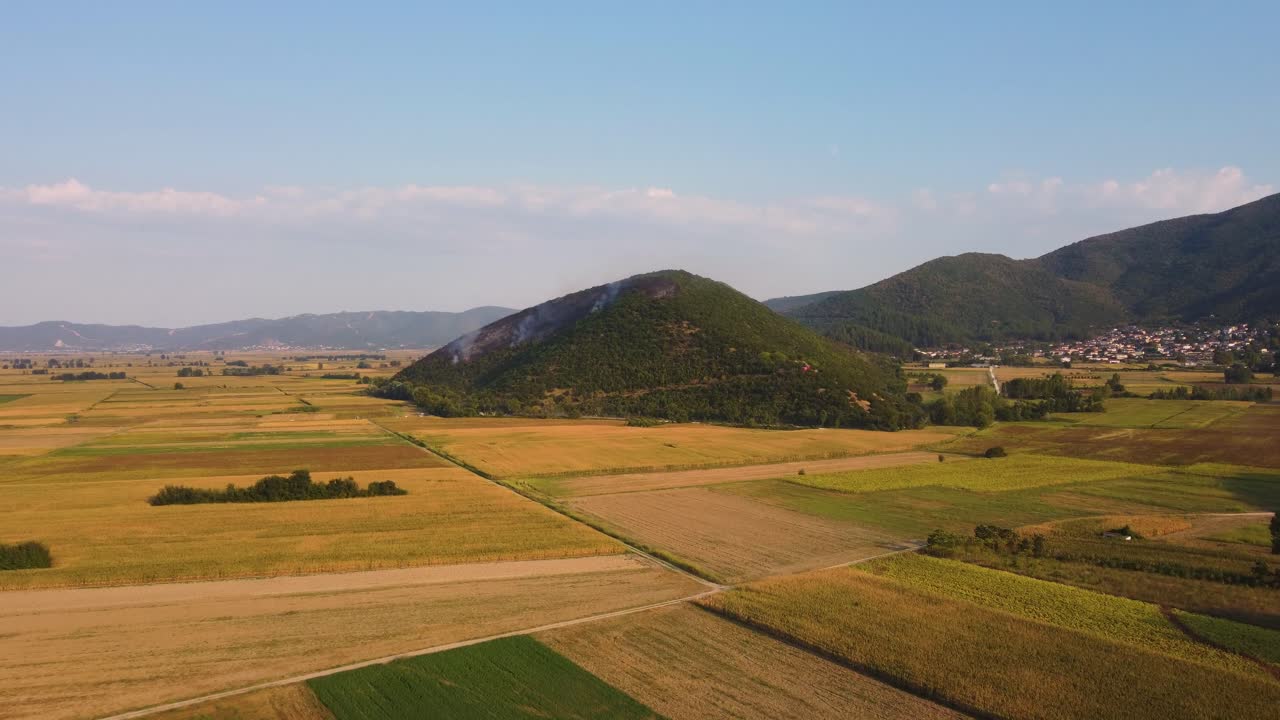 Inquadratura aerea d'insieme di un incendio boschivo su una collina sopra campi agricoli in Grecia