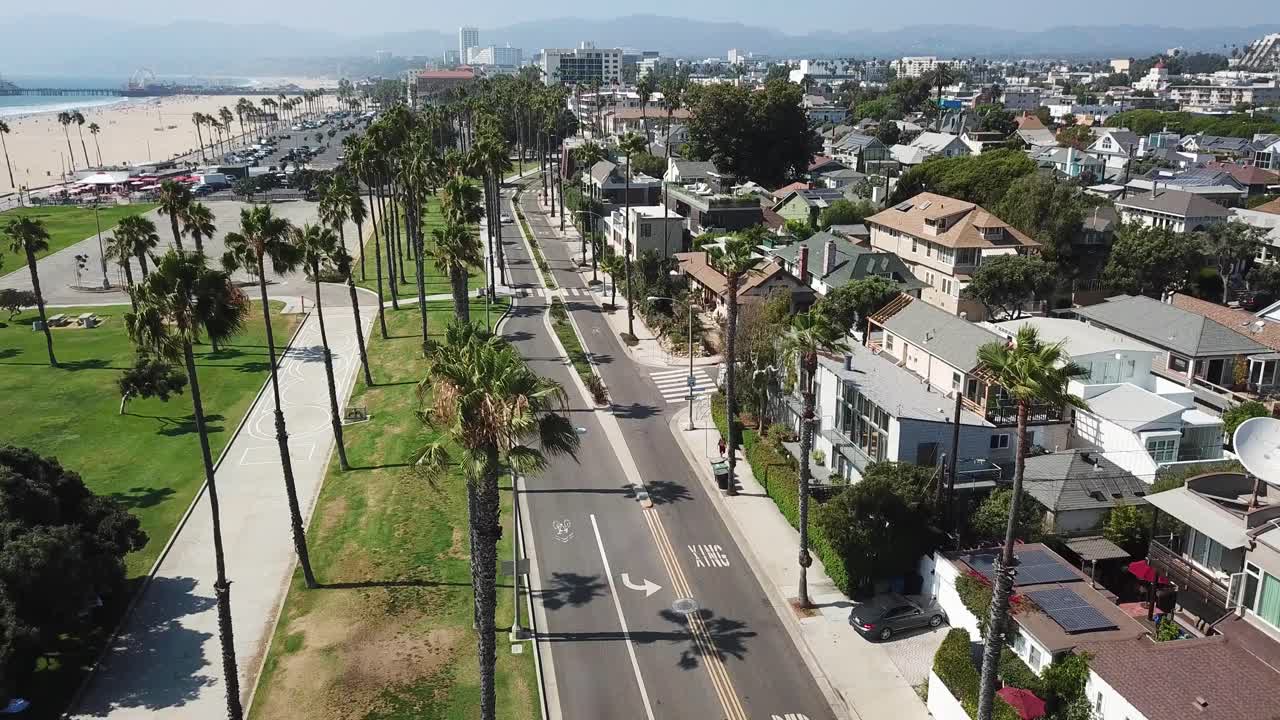Aerial descending view above Los Angeles beach suburb skyline down to waterfront neighbourhood street