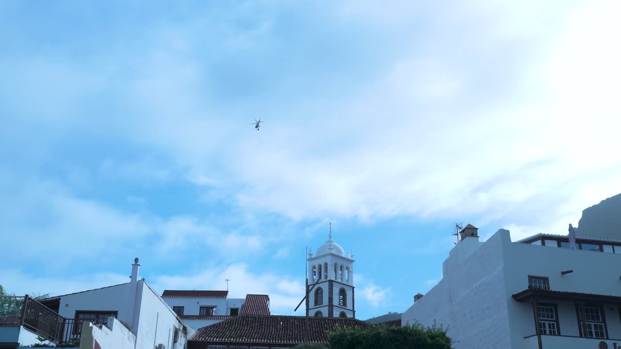 Elicottero che sorvola una città storica con una torre campanaria