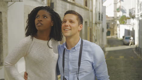 happy couple of tourists looking and pointing up.