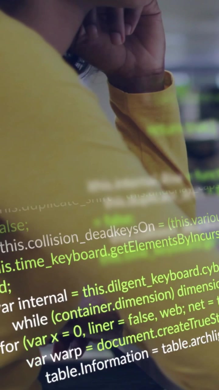 Vertical video: Coder leaning on desk watching screen, screen showing code scrolling across face