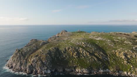 ocean waves splashing on the coast of sisargas island with an old lighthouse at the top, located in galicia, spain