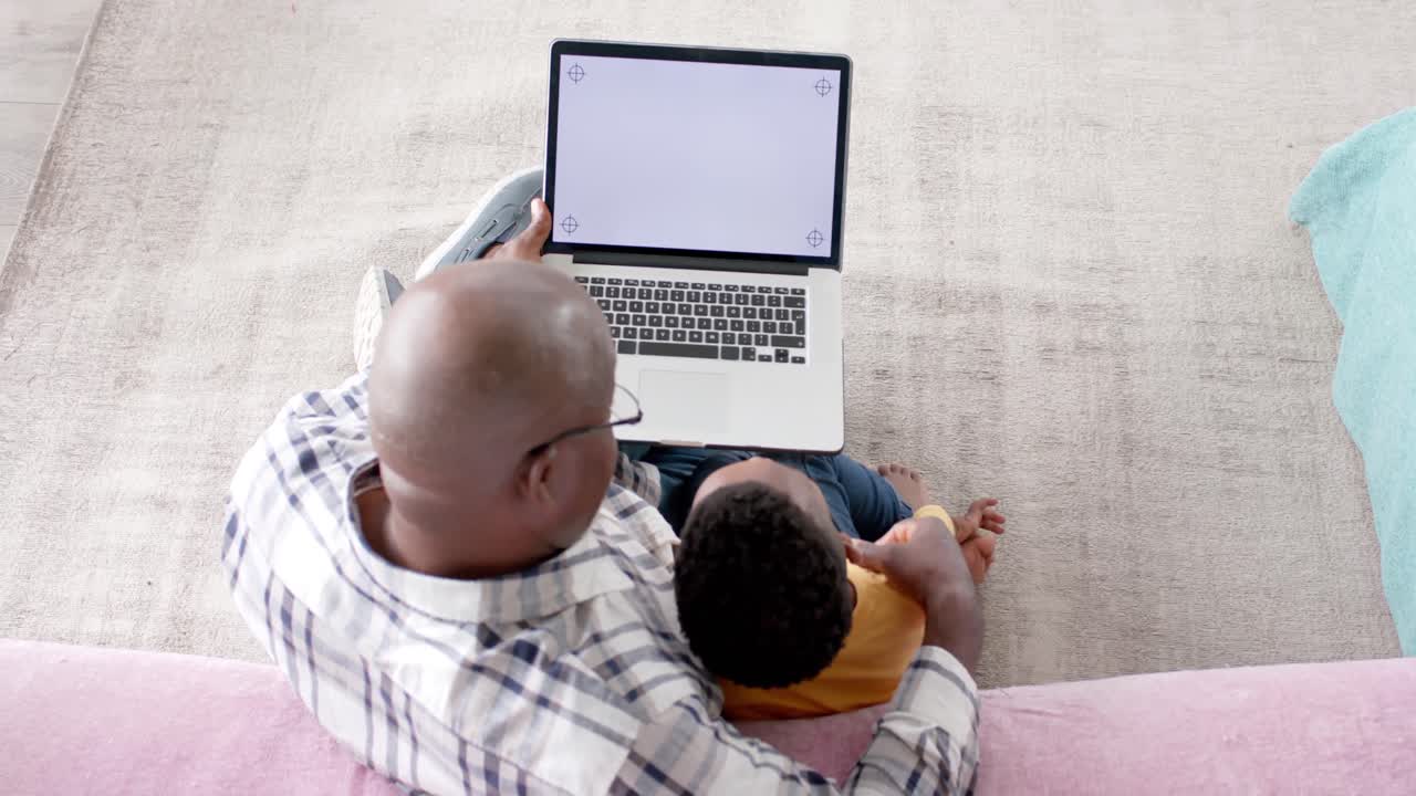 African american grandfather using tablet with grandson at home, slow motion, copy space on screen