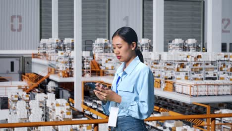 side view of asian business woman using mobile phone an looking around in the warehouse