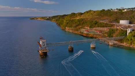 birds eye view rotating left drone shot of a sugar cane pier with jet ski cruising on the ocean located in aguadilla, puerto rico