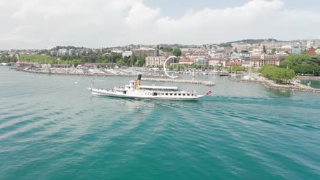 aerial of classic cruise ship sailing on lake geneva with the skyline of the city of lausanne, switzerland in the background